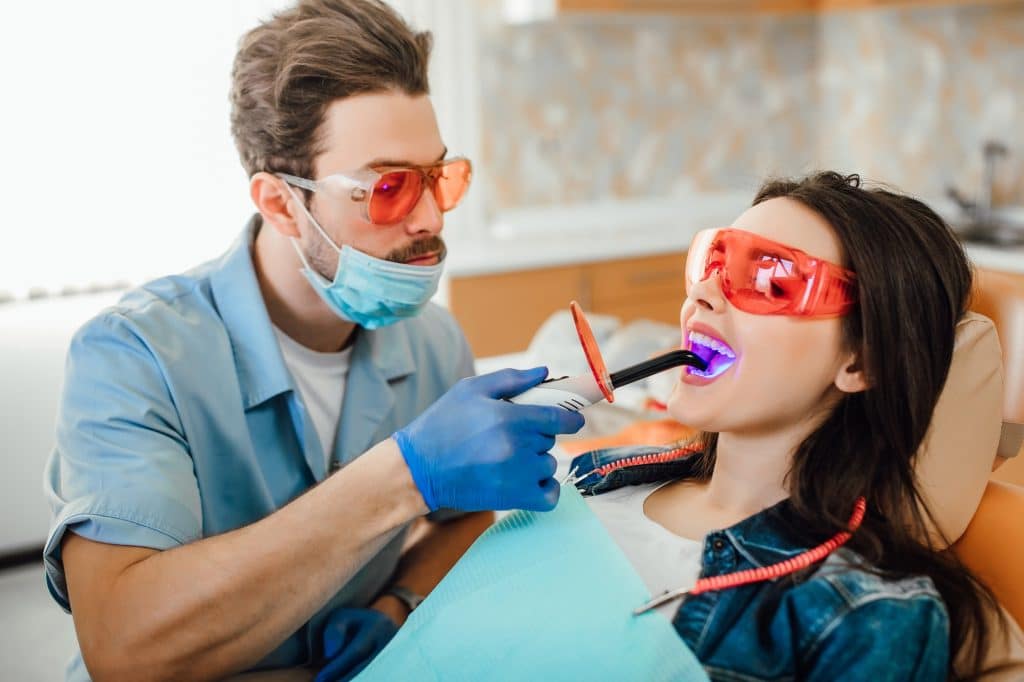 A dentist or dental hygienist performs a dental operation called teeth cleaning, also known as dental scaling, to remove plaque and tartar buildup from the teeth.