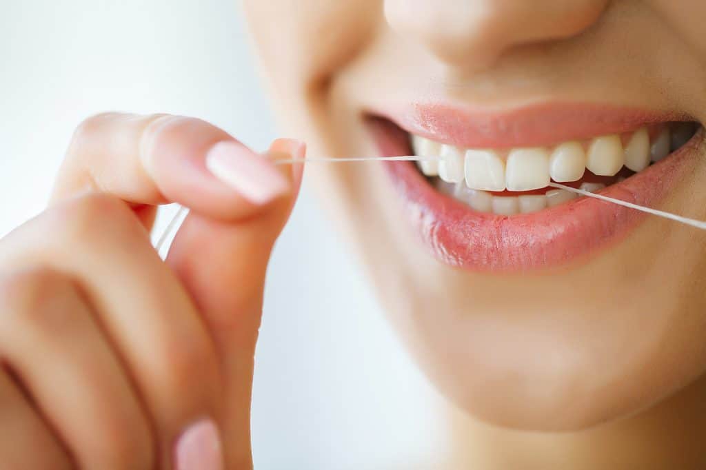 Using a fine thread or cord to scrape food debris and plaque from between teeth and along the gum line is the dental hygiene technique known as flossing. 